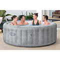 In use | Four adults sitting in the filled gray hot tub on a tiled patio