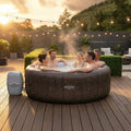 Patio | Five adults relaxing together in the bubbling spa on a lit deck at dusk