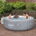 In use | Four adults relaxing together in the filled round hot tub on a stone patio