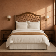 Clay room | Brown rattan headboard in a clay-toned bedroom with brass wall lights