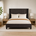 Airy room | Straight-on dark gray wingback bed in a bright bedroom with light wood nightstands and white curtains