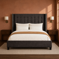 Clay room | Straight-on dark gray wingback bed against a warm clay wall with brass sconces and dark nightstands