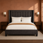 Clay room | Straight-on dark gray wingback bed against a warm clay wall with brass sconces and dark nightstands