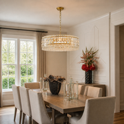 Scale view | gold-tone crystal drum chandelier hanging in a dining room beside a tall window and doorway