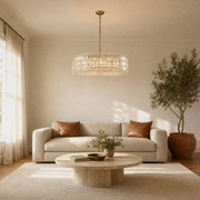 Living room | gold-tone crystal drum chandelier above an oatmeal sofa and travertine table