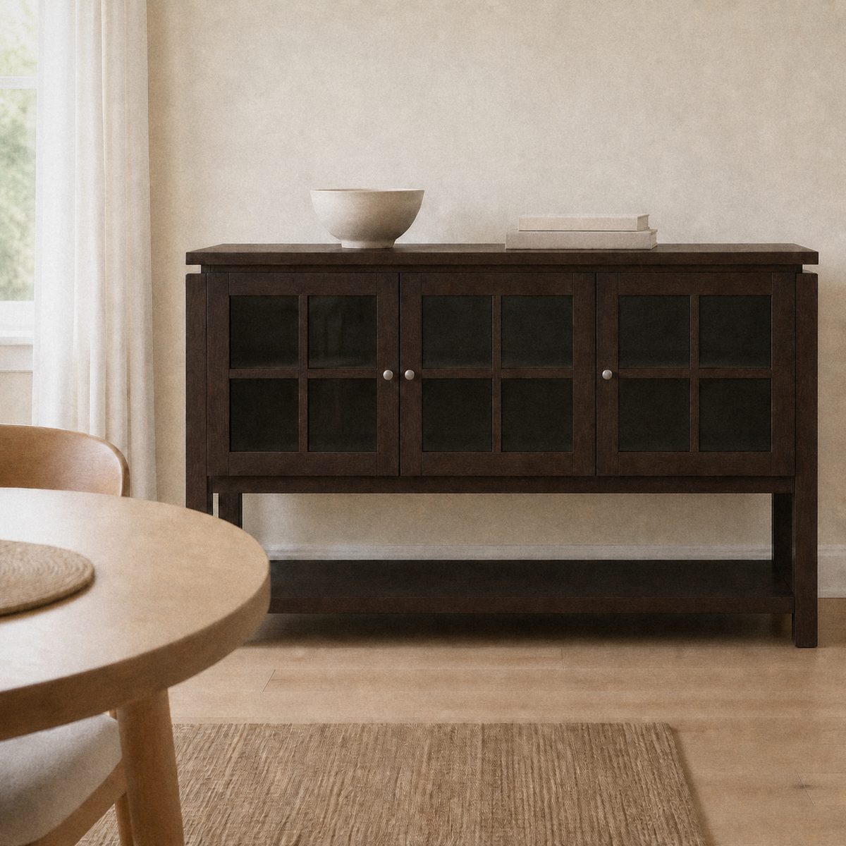 In a room | dark walnut 3-door sideboard against warm flax walls, round white-oak table at left, bright midday light across the glass doors