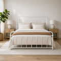 Airy room | White spindle bed in a bright room with a leafy plant, wood nightstands, and rug