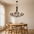 In a room | matte black 12-light wagon-wheel chandelier hanging over a round oak dining table