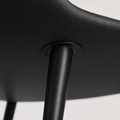 Closer | where a slim black metal leg meets the underside of the seat shell