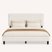Bedroom scene | Beige upholstered bed framed by a clay-toned wall and warm bedside lighting