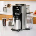 Angle | De'Longhi TrueBrew with thermal carafe on a kitchen counter, water tank and iced coffee glass alongside