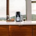 Lifestyle | De'Longhi TrueBrew with thermal carafe on a kitchen counter by a window, croissants and coffee beans alongside