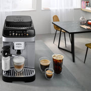 Lifestyle | Magnifica Evo espresso machine with LatteCrema carafe on a dining table pouring a latte macchiato with iced coffee and espresso nearby