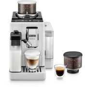 Front | white Rivelia straight on with the milk carafe fitted, a cappuccino under the spout, an espresso and a spare bean hopper beside it