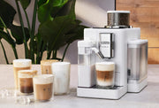 Lifestyle | white Rivelia on a countertop pouring an iced latte, with iced coffee drinks lined up beside it