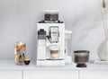 Lifestyle | White espresso machine on a countertop with an iced latte and a cappuccino brewing