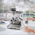 In use | a hand prepares a coffee drink beside the stainless espresso machine