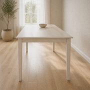 Angle | same dining room, low three-quarter from the table's near end, long side receding toward the window