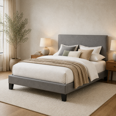 Room 1 angle | Gray upholstered frame seen from the foot corner with the rectangular headboard and dark legs