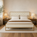 In a room | Straight-on bedroom view of the cream upholstered bed with gold frame, wood nightstands, and table lamps
