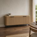 In a plaster dining room | reeded sideboard against warm ivory plaster walls and smoked oak floor, sheer curtain at right