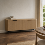 In a plaster dining room | reeded sideboard against warm ivory plaster walls and smoked oak floor, sheer curtain at right