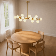 Angle | second angle of the Marnau Glazenn 16-light sputnik chandelier over the round wood dining table, showing the fixture's staggered globes from the side