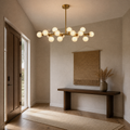 In a room | marnau Glazenn 16-light sputnik chandelier hung in an entryway with a dark wood front door, jute wall hanging, console table, and jute runner rug