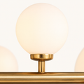 Texture | close-up of one frosted glass globe on the Marnau Glazenn chandelier, showing the brushed brass collar and stem where it meets the bar