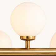 Texture | close-up of one frosted glass globe on the Marnau Glazenn chandelier, showing the brushed brass collar and stem where it meets the bar