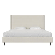 Studio front | Textured ivory canvas wingback bed with bedding, straight headboard and black tapered legs