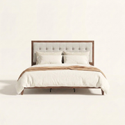 Studio front | Walnut platform bed with square-tufted light linen headboard and tapered legs