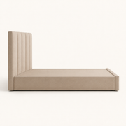 Studio side | Side profile of the beige upholstered bed showing the headboard, footboard depth, and low plinth base