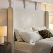 Wing detail | Ivory canvas headboard beside layered neutral bedding