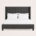 Studio front | Charcoal button-tufted wingback bed with squared wings, silver nailhead trim, and a low upholstered footboard