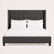 Studio front | Charcoal button-tufted wingback bed with squared wings, silver nailhead trim, and a low upholstered footboard