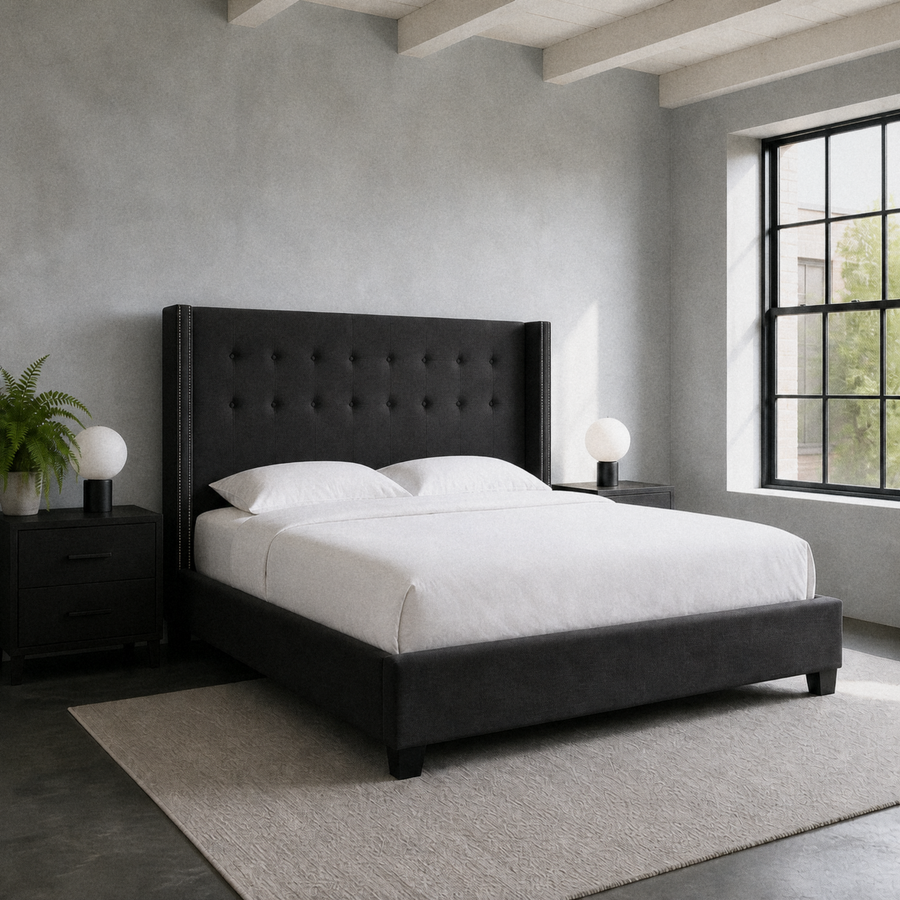 Cool loft bedroom | Charcoal wingback bed in a blue-gray room with black nightstands, globe lamps, and a plain gray rug