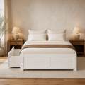 In a room | White storage platform bed styled with neutral bedding, wood nightstands, lamps, and a warm area rug