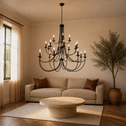 Living room | black 20-light chandelier above a round travertine table in a warm living room with sofa and olive tree