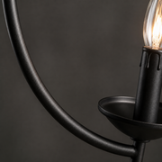 Material | close view of the matte black curved arm, candle cup, and clear flame-shaped bulb