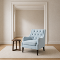 Room scale | pale ice-blue tufted wingback chair beside a full-height interior doorway