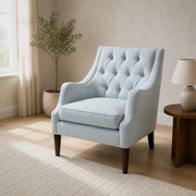 Airy living room angle | pale ice-blue tufted wingback chair with a window, olive tree, and dark wood side table