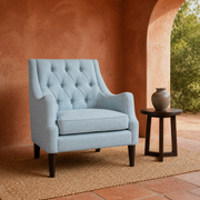 Terracotta garden room | pale ice-blue tufted wingback chair on a natural woven rug by an arched opening