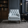Blue-gray library | pale ice-blue tufted wingback chair with a dark wood bookcase and brass floor lamp