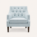 Studio front | pale ice-blue woven wingback chair with ten fabric-covered buttons, piped seat cushion, and dark tapered wood legs