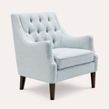 Studio three-quarter | pale ice-blue wingback chair showing curved arms, deep seat, and dark tapered legs