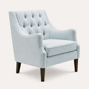 Studio three-quarter | pale ice-blue wingback chair showing curved arms, deep seat, and dark tapered legs
