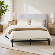 Bright corner | Angled bright bedroom view of the headboard with oak nightstands, lamps, a plant, and a rug