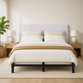 Bright room | Front view of the upholstered headboard in a bright bedroom with oak nightstands, lamps, a plant, and a rug