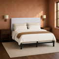 Clay corner | Angled clay bedroom view of the headboard with sconces, dark nightstands, a window, and a rug